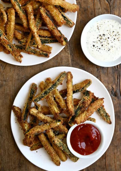 Crispy zucchini fries on a plate with a small bowl containing ketchup.