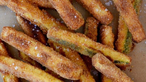 A pile of zucchini fries next to a bowl containing ranch dressing.