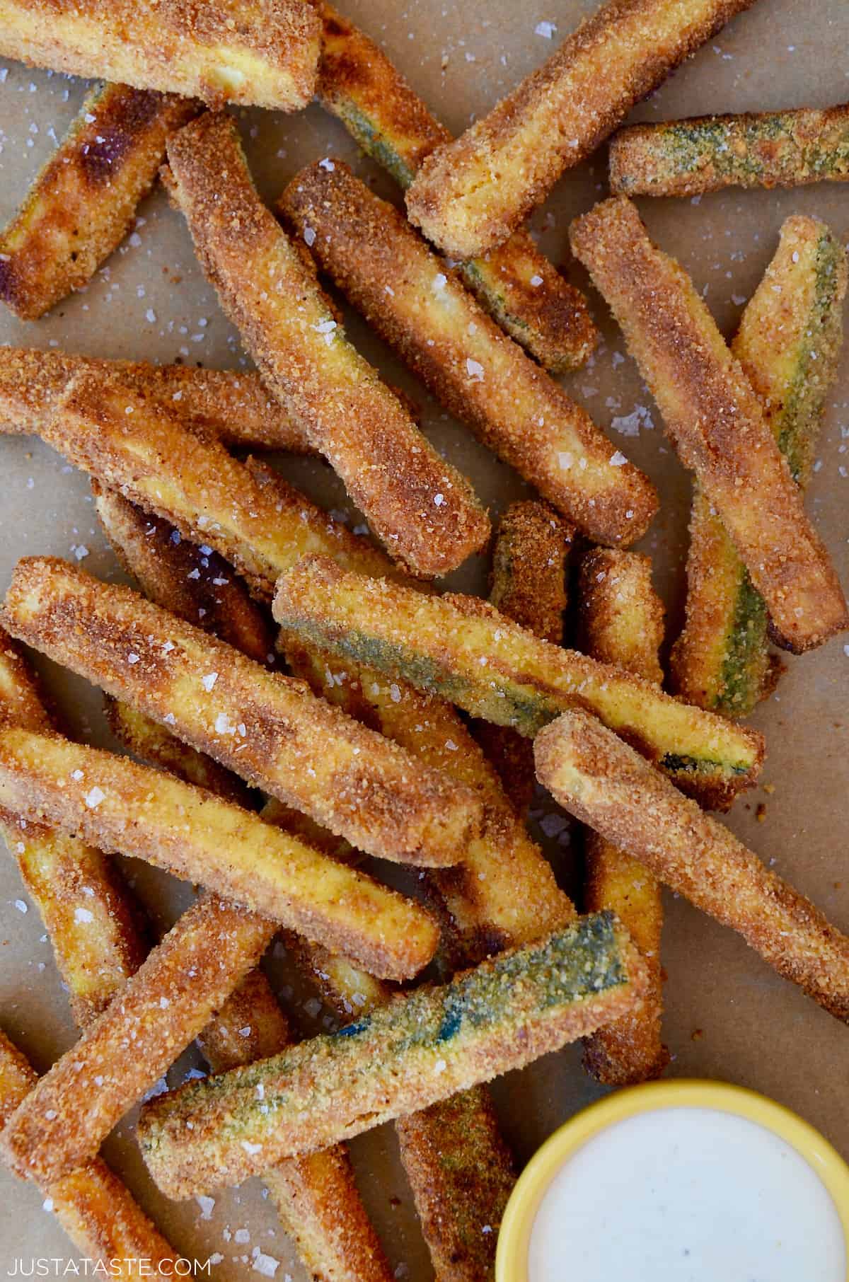 A pile of zucchini fries next to a bowl containing ranch dressing.
