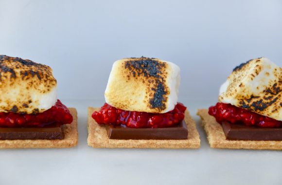 Three toasted marshmallows on graham crackers with fresh raspberries