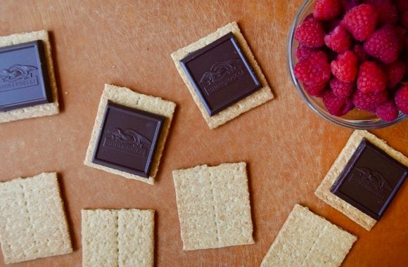 Graham crackers, chocolate and raspberries on a cutting board