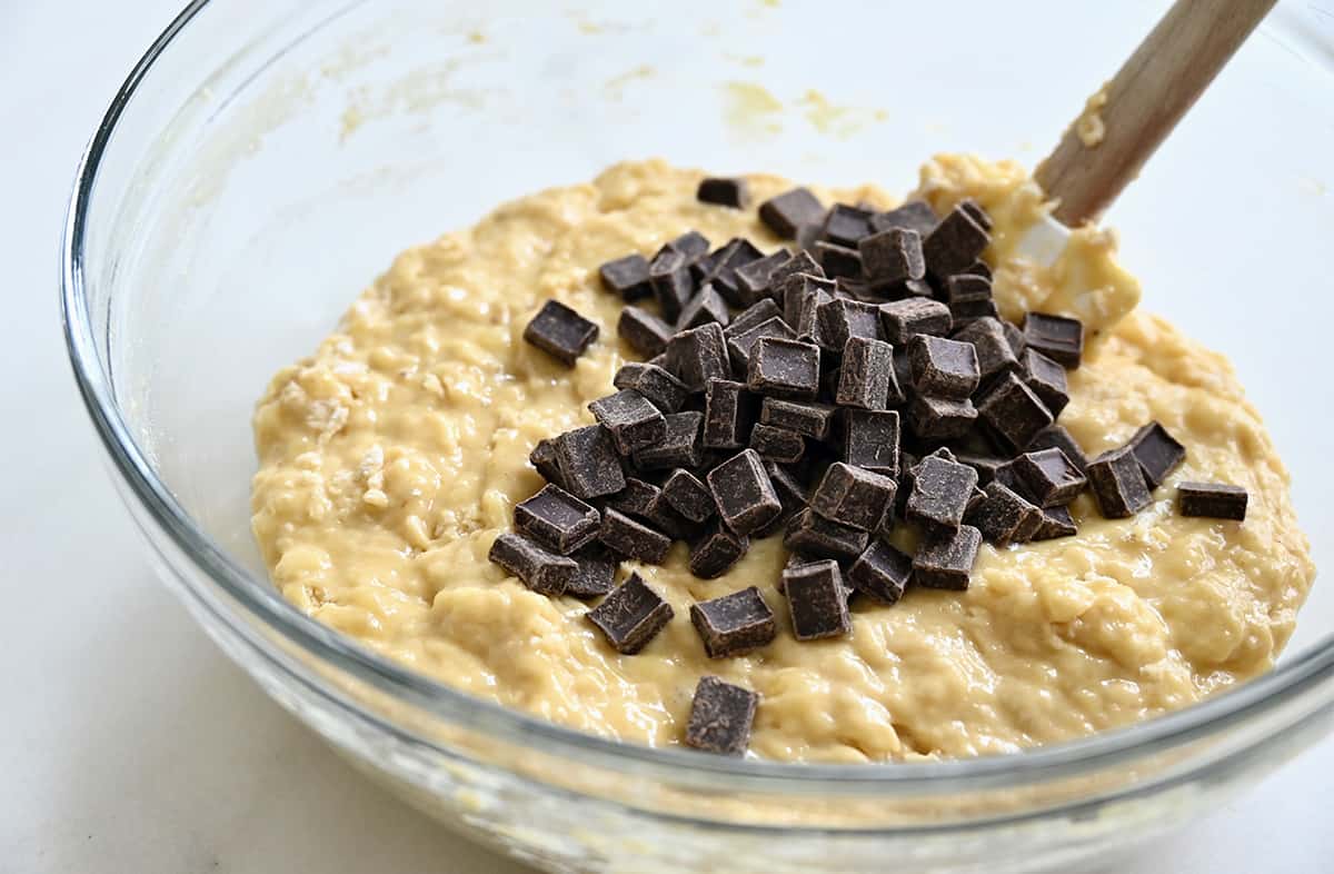 A clear bowl with banana bread batter and chocolate chunks.