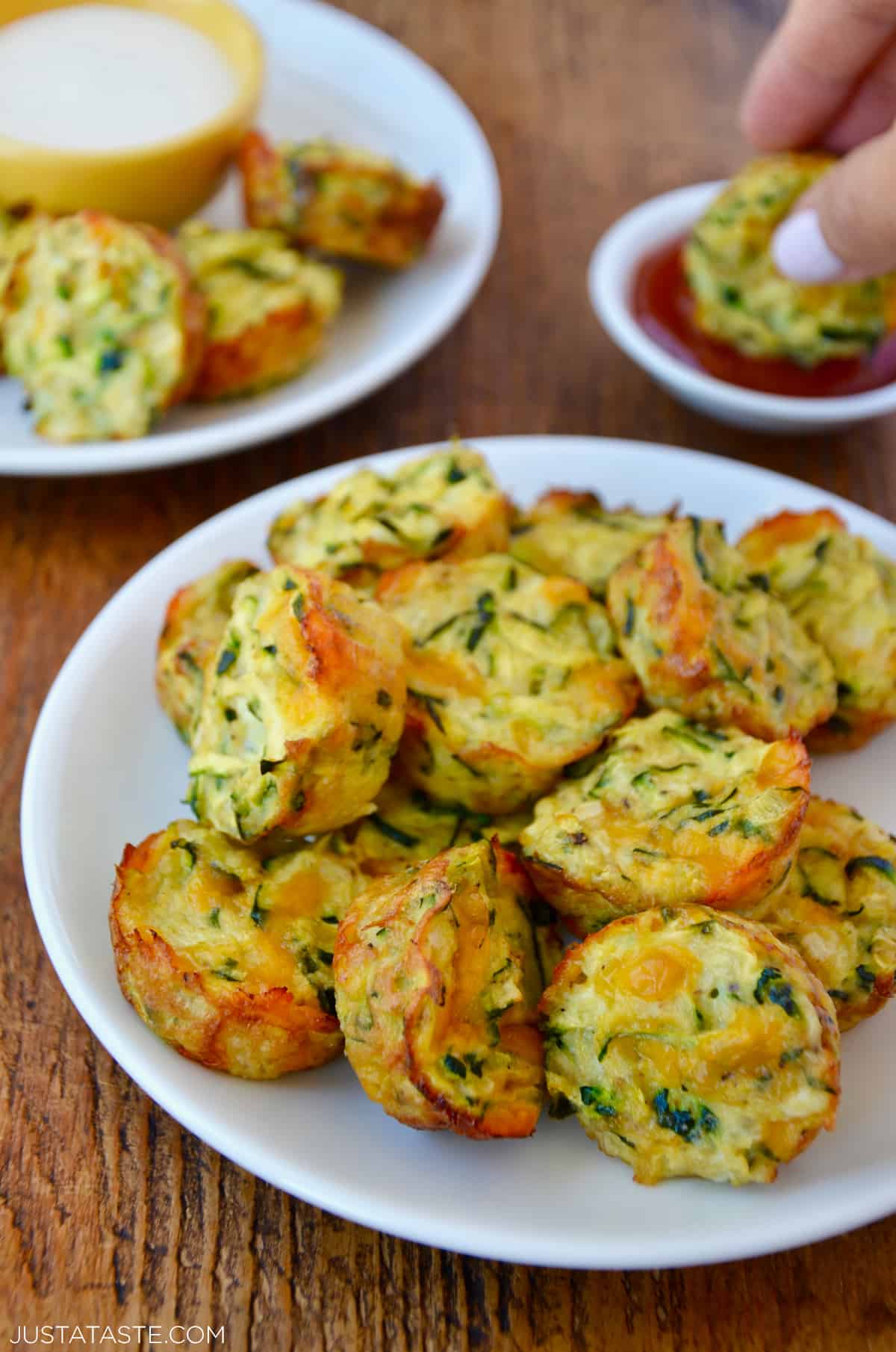Cheesy baked zucchini tots piled high on a white plate.