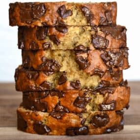 Slices of chocolate chunk banana bread stack atop each other.