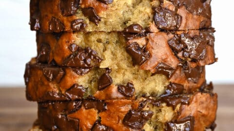 Slices of chocolate chunk banana bread stack atop each other.