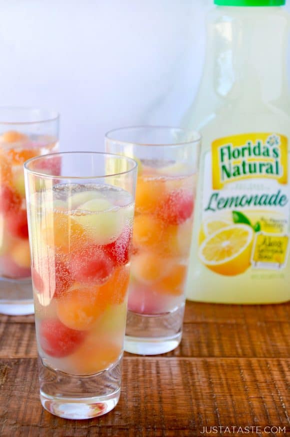 Clear cocktail glasses with melon balls and a bottle of lemonade