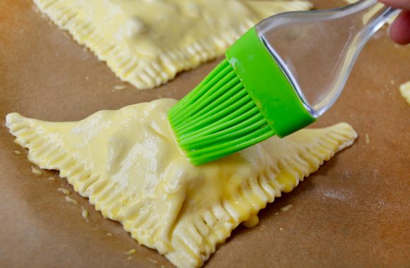 Brushing egg wash on top of apple turnovers