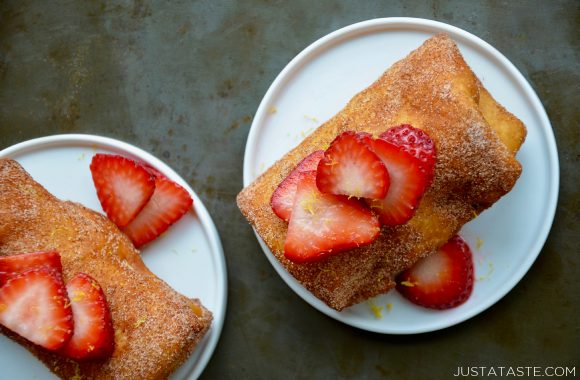 Two white plates on a grey background containing strawberry cheesecake chimichangas