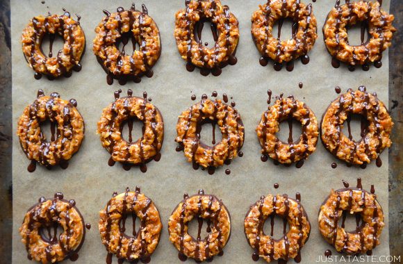 A baking sheet filled with rows of homemade Samoas Girl Scout cookies drizzled with chocolate