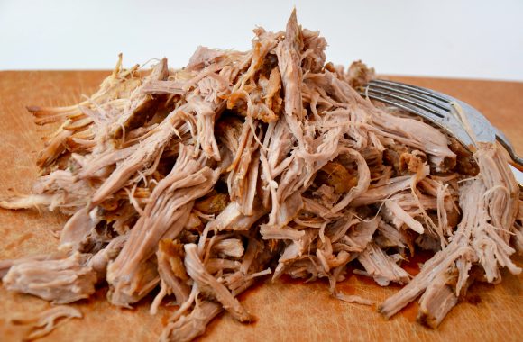 Pile of pulled pork with fork on cutting board