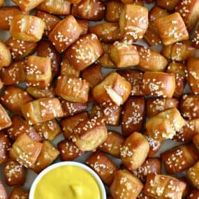 A close-up view of Easy Homemade Soft Pretzel Bites surrounding a small ramekin filled with yellow mustard