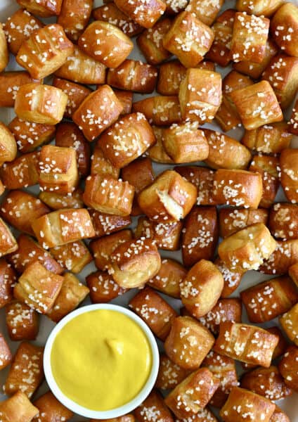 A close-up view of Easy Homemade Soft Pretzel Bites surrounding a small ramekin filled with yellow mustard