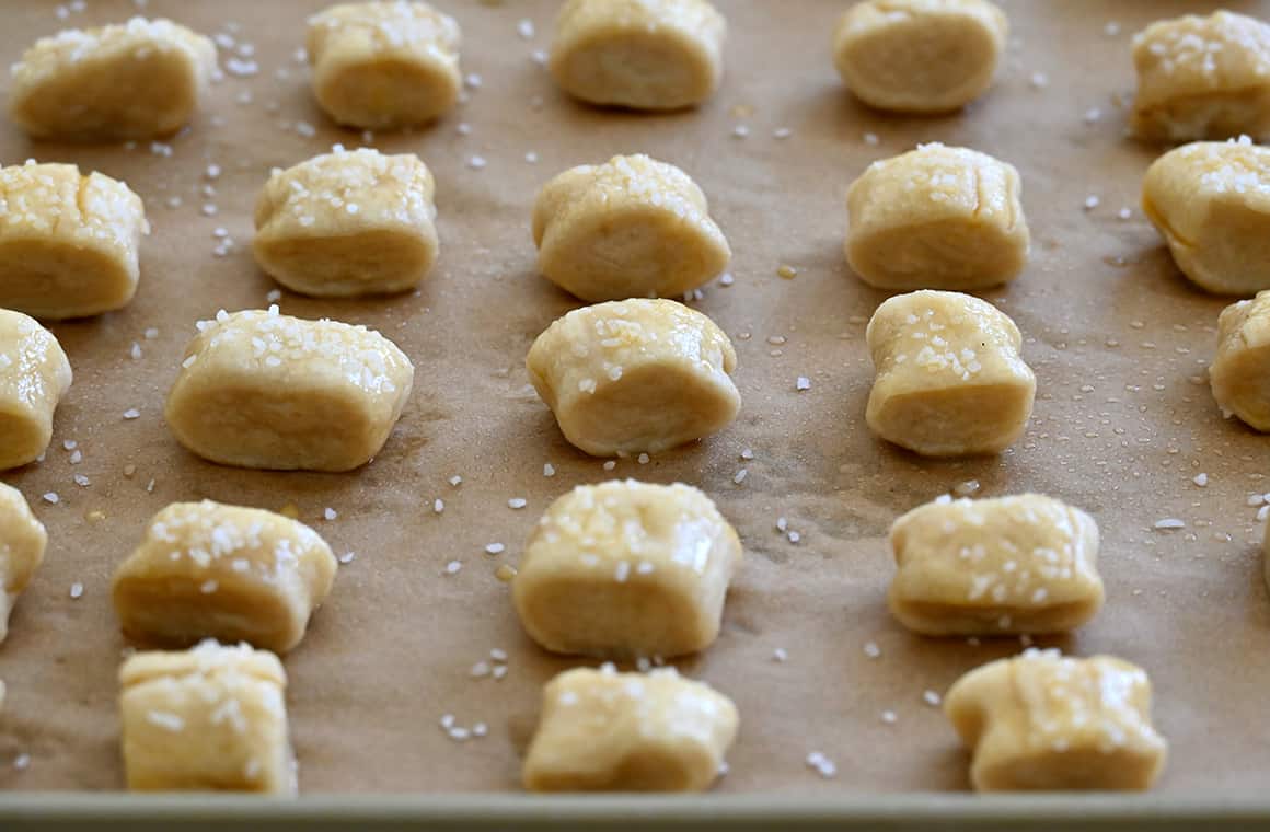 Unbaked soft pretzel bites topped with egg wash and sea salt on a parchment paper-lined baking sheet