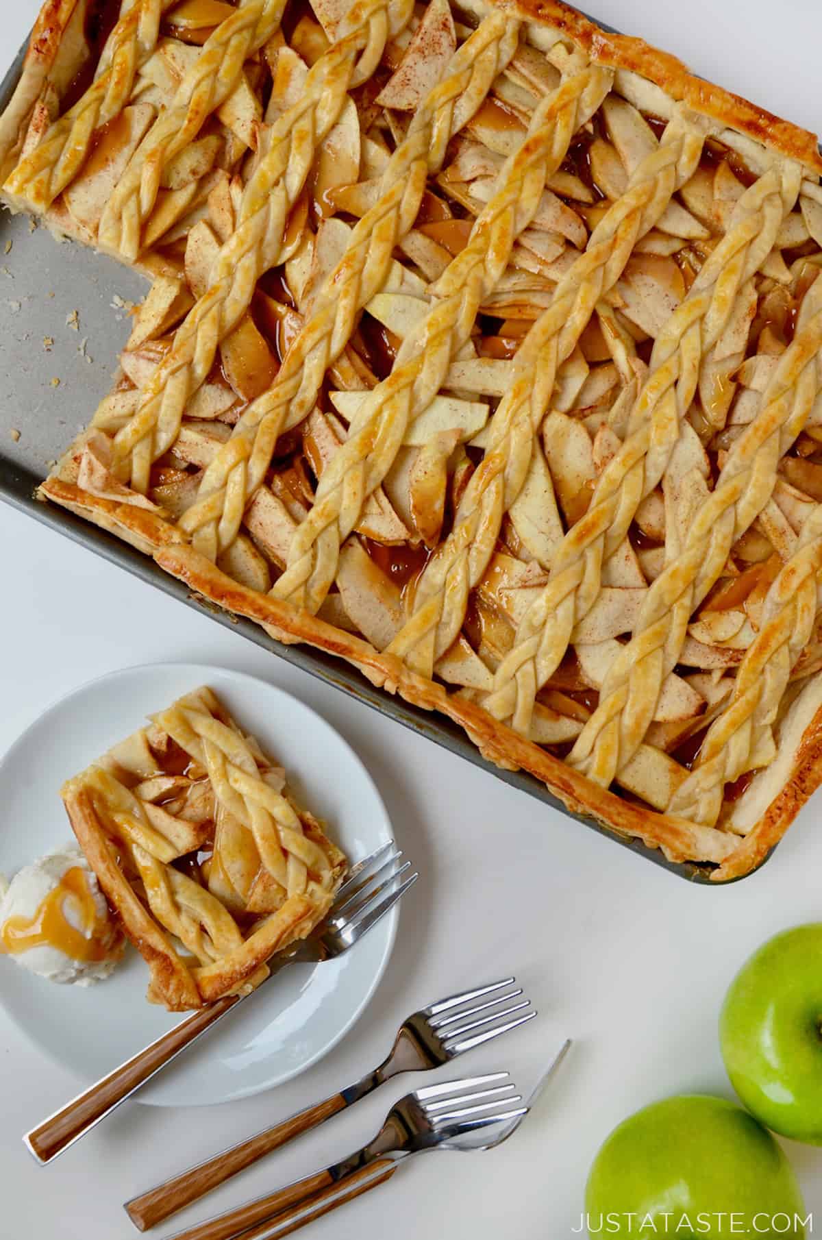 A sheet pan with caramel apple slab pie with a lattice topping next to a plate with a slice of pie and a scoop of vanilla ice cream.