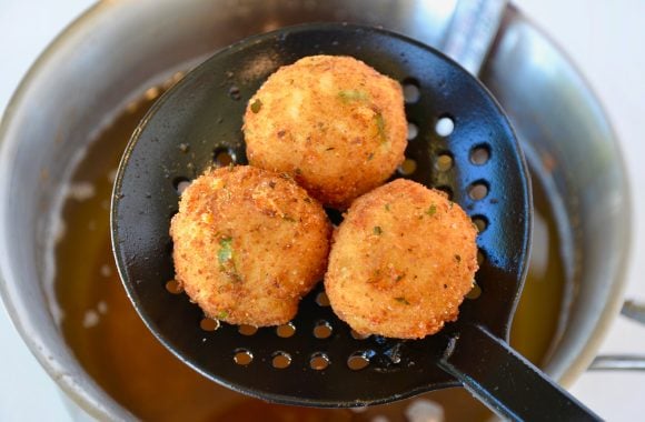 Fried Leftover Mashed Potato Balls in slotted spoon above pot of oil 