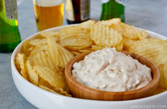 Homemade Sour Cream and Onion Dip in small bowl surrounded by potato chips in serving tray