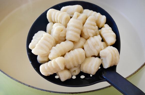 Mashed potato gnocchi in slotted spoon over large pot