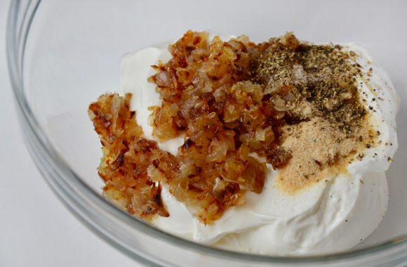 Sour cream, caramelized onions and garlic powder in clear bowl