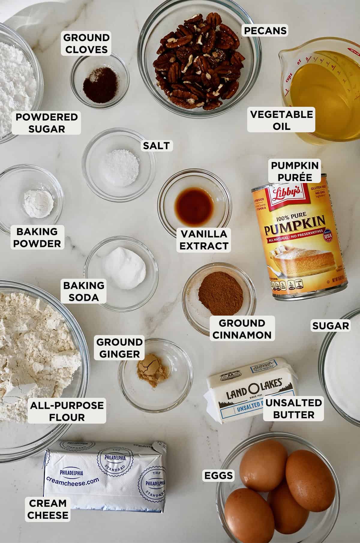 Ingredients to make pumpkin bars with cream cheese frosting in various sizes of glass bowls.