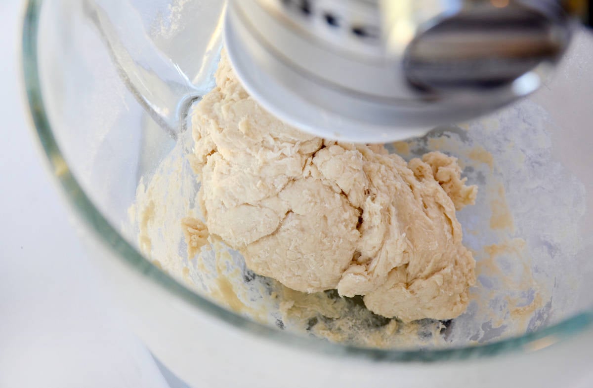 Bread dough in the bowl of a stand mixer with a paddle attachment.