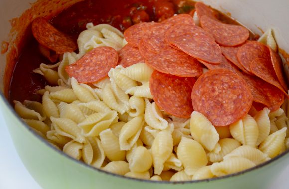 Tomato sauce, cooked pasta and pepperoni in stock pot