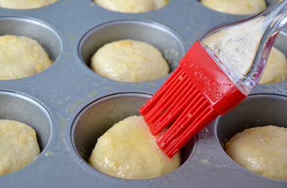 Brushing tops of unbaked pizza pockets with garlic butter