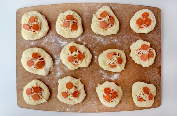 Making pizza pockets filled with shredded mozzarella cheese and pepperonis