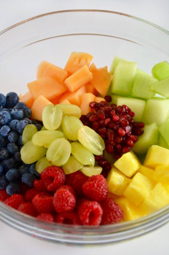 A glass bowl containing fruit salad separated by fruit