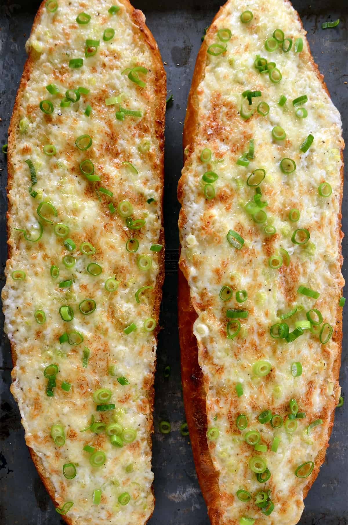 Two cheesy garlic mayo bread loaves garnished with sliced green onions.