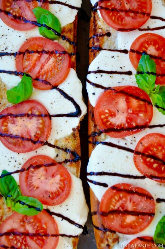 A top down view of two halves of Caprese Garlic Bread drizzled with balsamic syrup