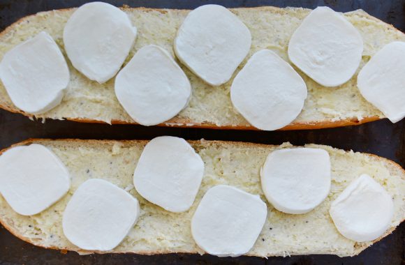 Two halves of bread with garlic butter and fresh mozzarella cheese