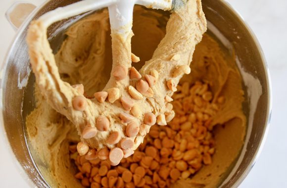 Closeup of paddle attachment of stand mixer with peanut butter blondies batter and peanut peanut butter chips