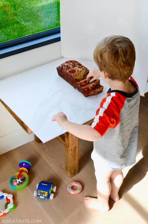 A child standing in front of a loaf of Raspberry Chocolate Chip Banana Bread