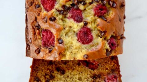 A top down view of a loaf of Raspberry Chocolate Chip Banana Bread cut into slices