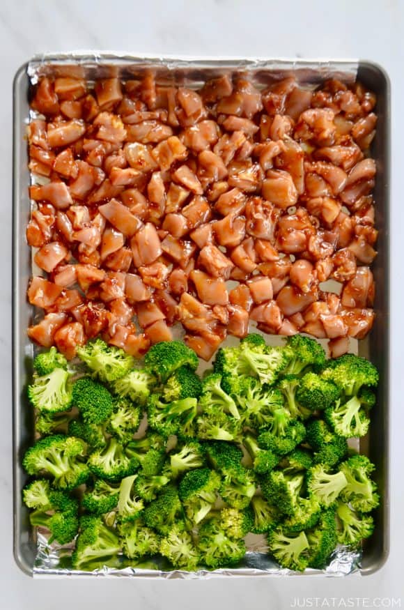 Foil-lined baking sheet with diced chicken thighs and broccoli florets