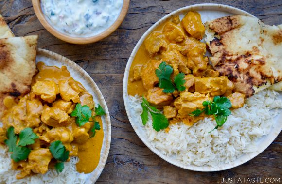 Bowl with yogurt and two plates containing The Best Chicken Tikka Masala with white rice and naan 