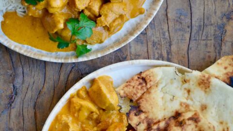 Two plates containing The Best Chicken Tikka Masala with cilantro, white rice and naan