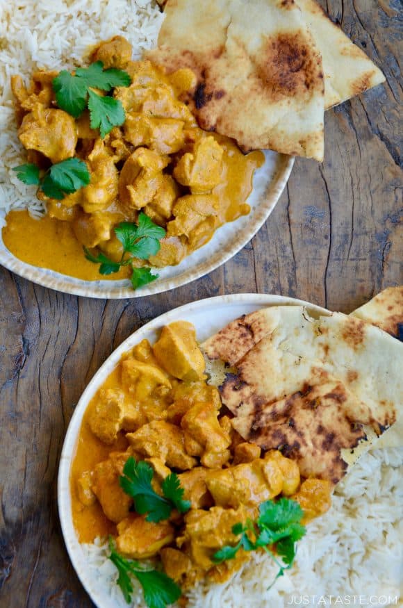 Two plates containing The Best Chicken Tikka Masala with cilantro, white rice and naan