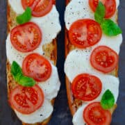 Top-down view of a loaf of French bread cut in half and topped with fresh mozzarella, sliced tomatoes and fresh basil leaves.