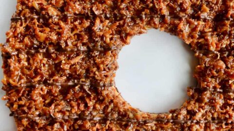 A top down view of a Giant Samoas Cookie Cake with a female hand touching it