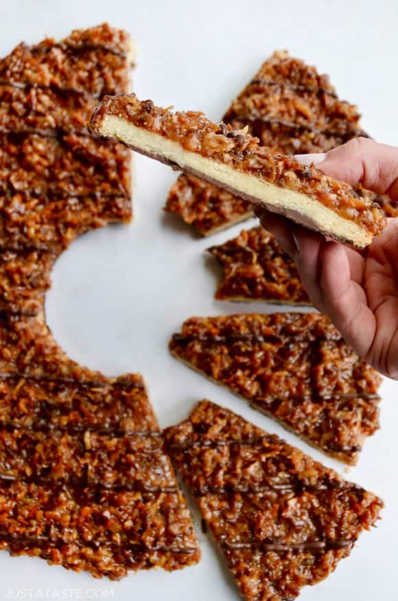 A close-up shot of a hand holding a slice of samoas cookie cake