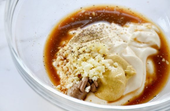 Bowl containing homemade caesar dressing ingredients