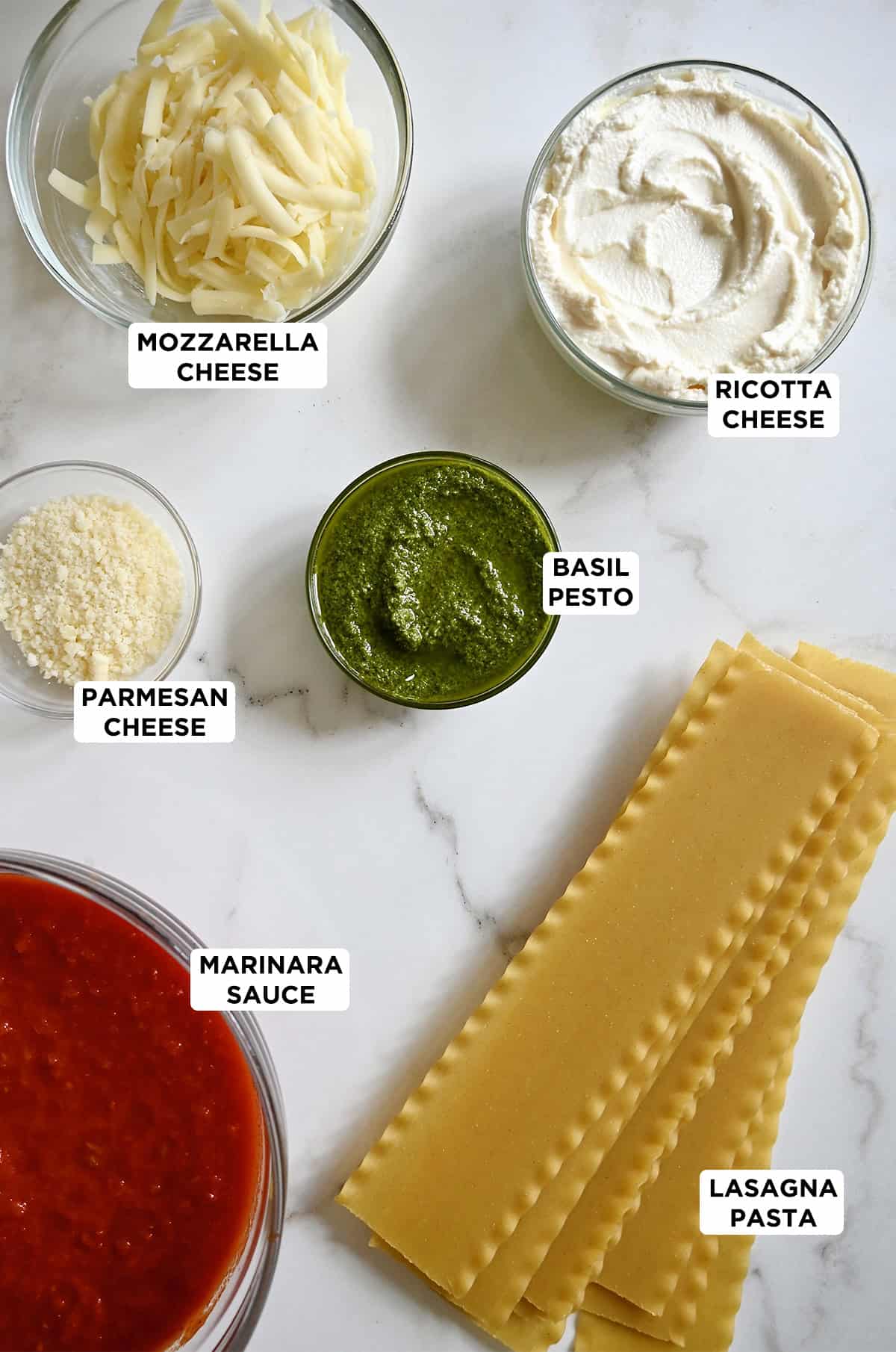 Lasagna roll-ups ingredients, including marinara sauce, pesto, lasagna noodles, ricotta, Parmesan and mozzarella.