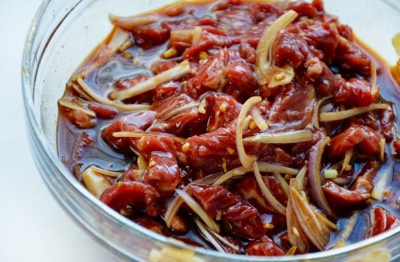 Sliced beef in clear bowl with marinade