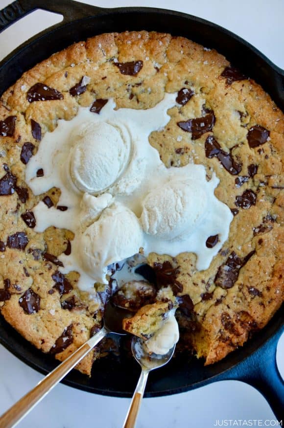 Spoons in the best skillet chocolate chip cookie topped with vanilla ice cream