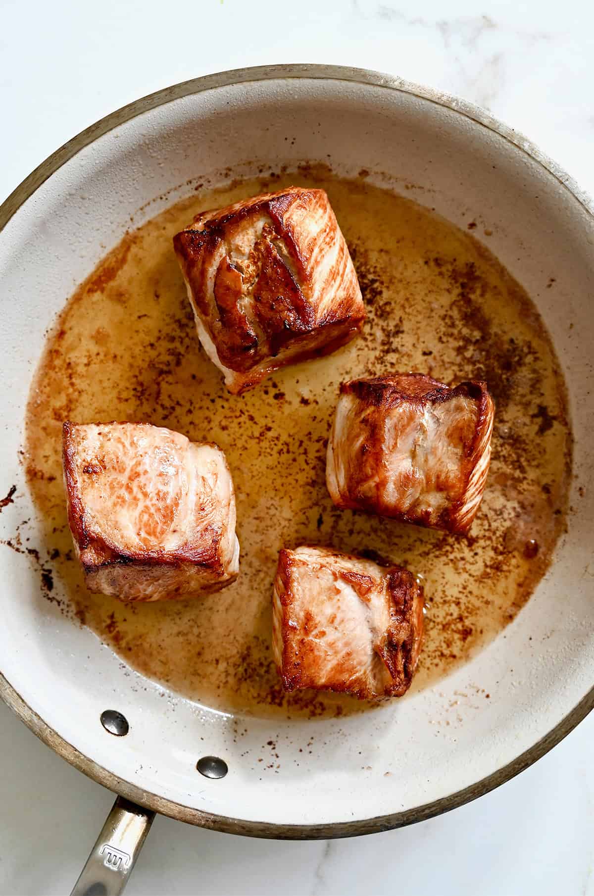 Browning pork shoulder in a skillet.