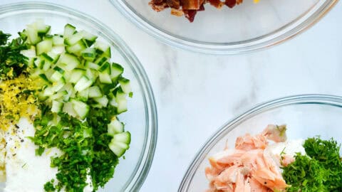 Three bowls containing flavored cream cheese: smoked salmon, bacon-scallion and garlic-herb.
