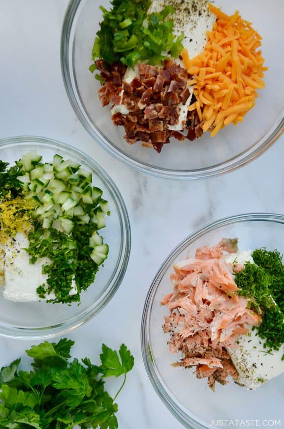 Three clear bowls containing cream cheese and various other ingredients