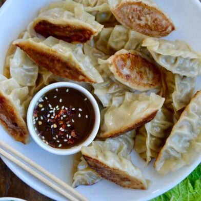 Pork Potstickers with Citrus-Soy Dipping Sauce on white plate with chopsticks