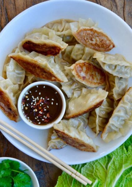 Pork Potstickers with Citrus-Soy Dipping Sauce on white plate with chopsticks